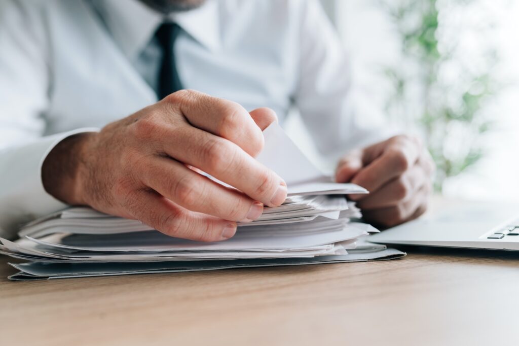 HR manager reading employee candidates resumes piled on office desk